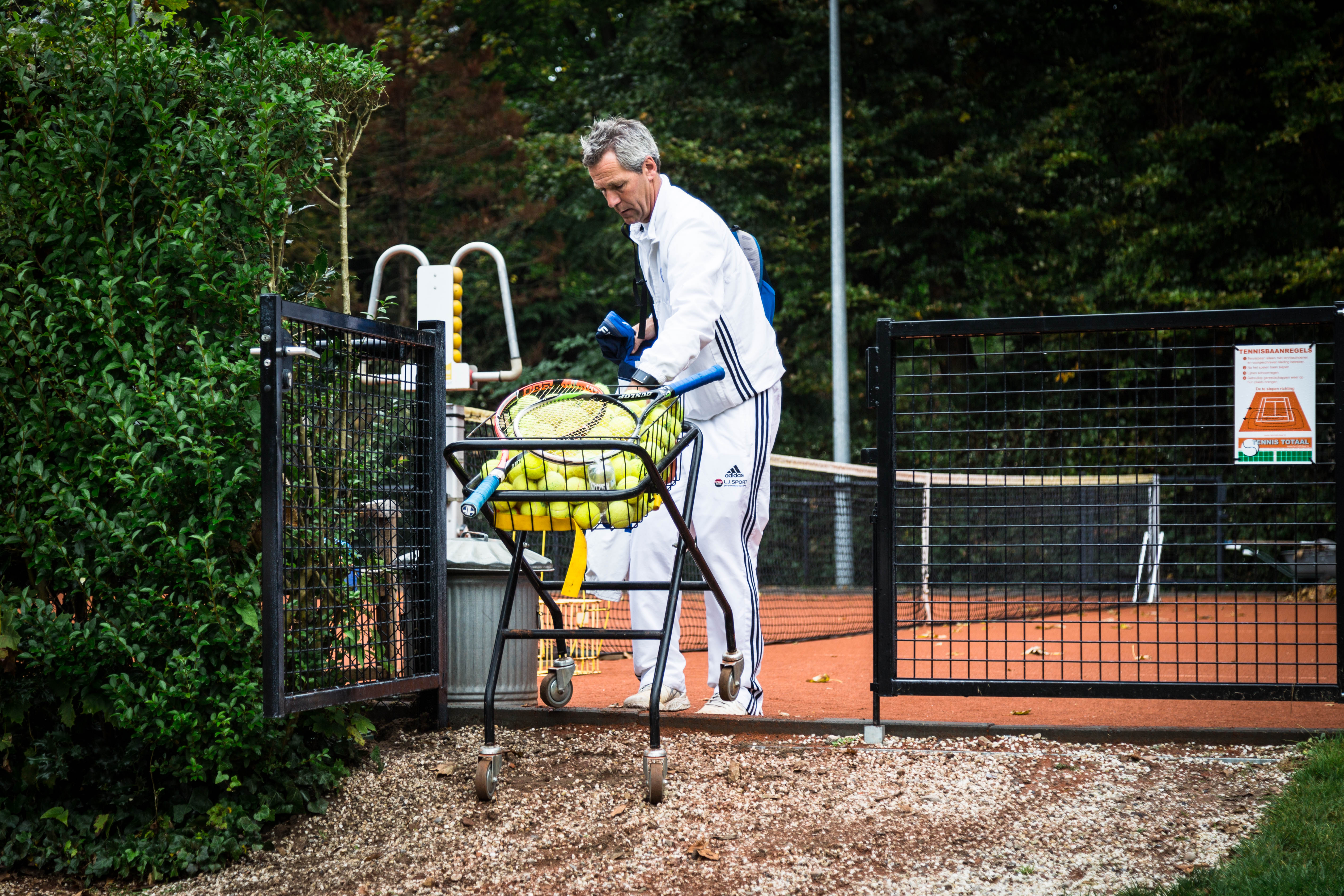 Tennisleraar de baan op